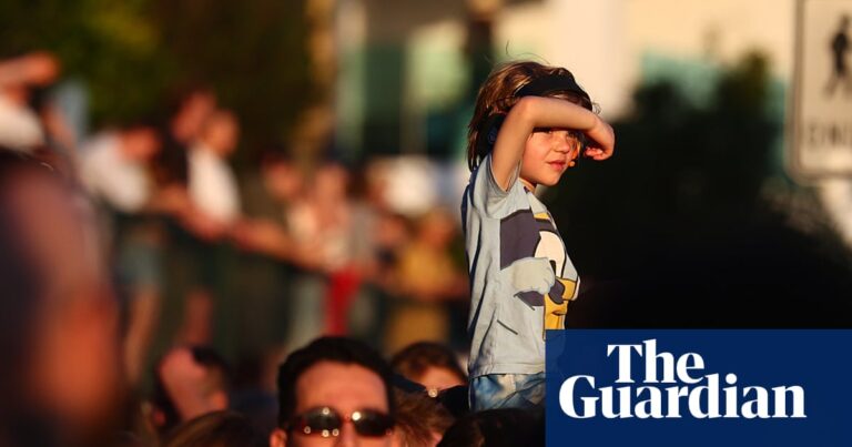A boy sits on someone's shoulders shielding his eyes, above a crowd watching Riverfire