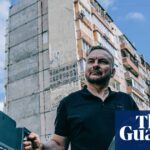 Serhii Beskrestnov holds a spectrum analyser near damaged apartment buildings in Kyiv