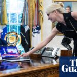 Donald Trump looks on as Natalie Harp, an aide, places a computer displaying a news report about the stock market, on his desk.