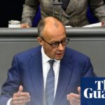 Friedrich Merz gestures with both hands while speaking at a podium in the Bundestag