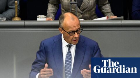 Friedrich Merz gestures with both hands while speaking at a podium in the Bundestag