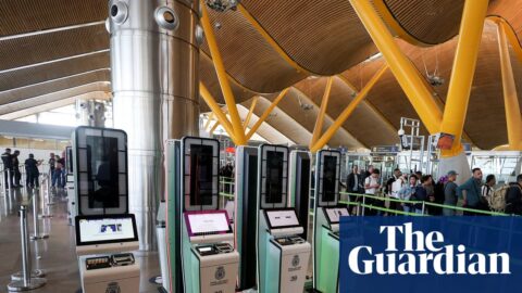 Automated EES kiosks stand near a queue of travellers at Madrid's Barajas Airport