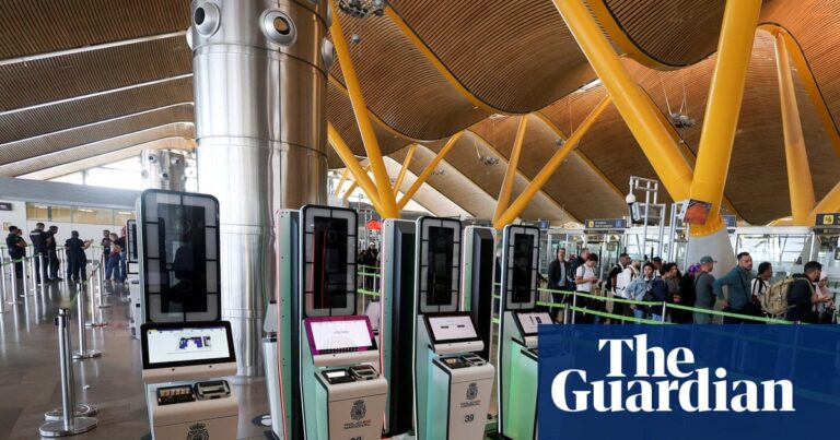 Automated EES kiosks stand near a queue of travellers at Madrid's Barajas Airport