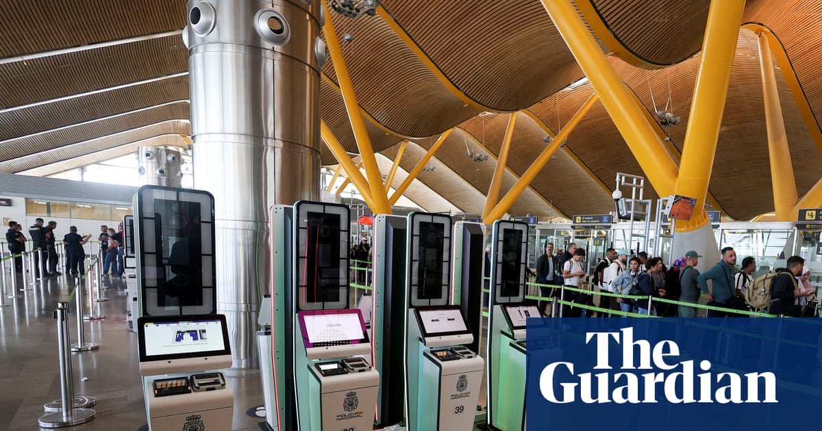 Automated EES kiosks stand near a queue of travellers at Madrid's Barajas Airport