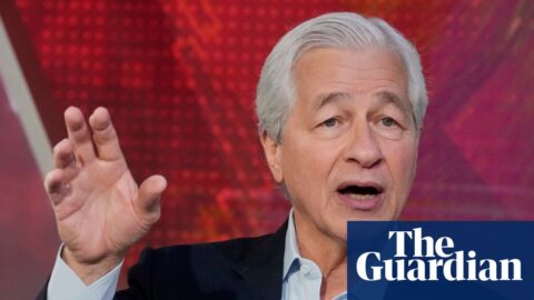 Jamie Dimon gestures with his raised hand while speaking during a TV interview