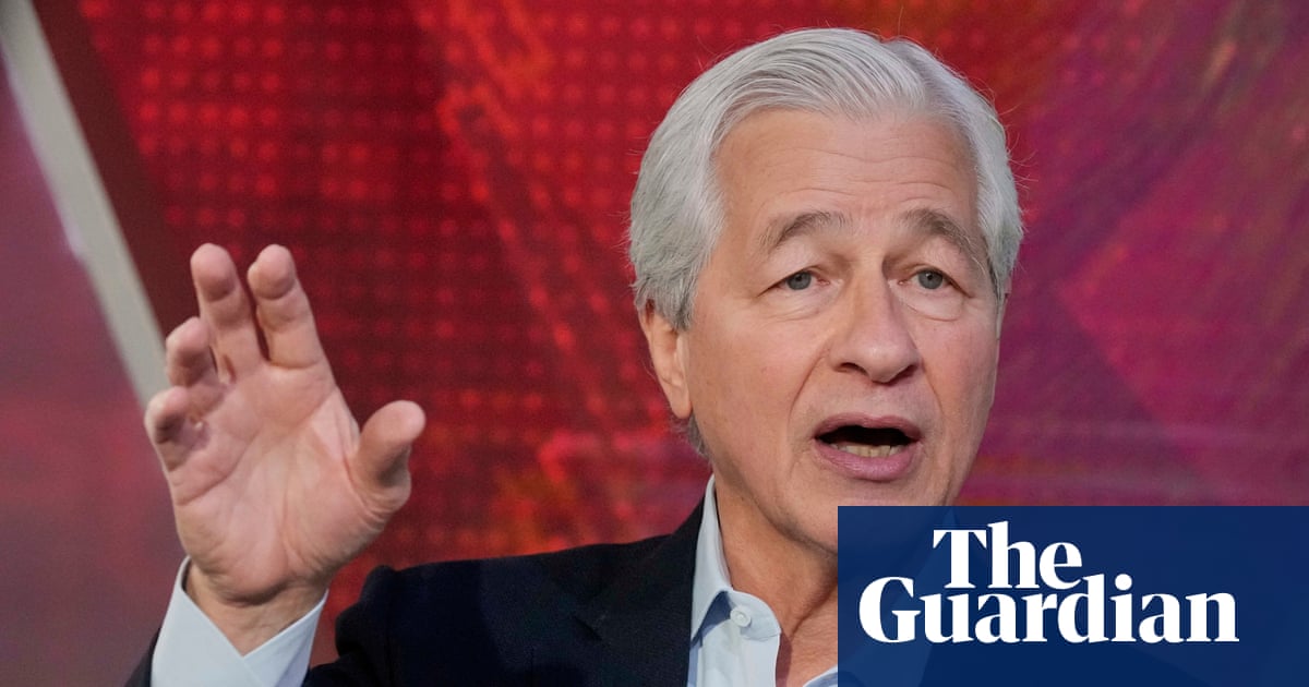 Jamie Dimon gestures with his raised hand while speaking during a TV interview