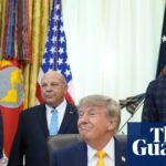 Man sits at desk and smiles as people stand behind him