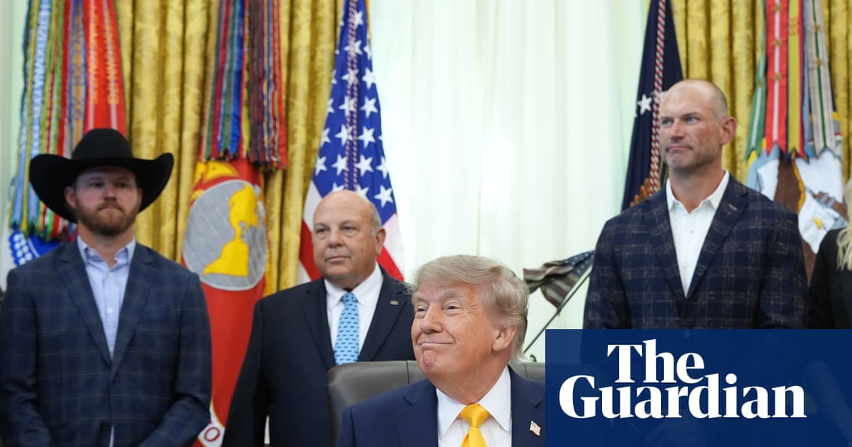 Man sits at desk and smiles as people stand behind him