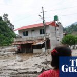 A woman looks on as heavy machinery works in the aftermath of deadly flash floods and a mudslide near the Nepal-Tibet border