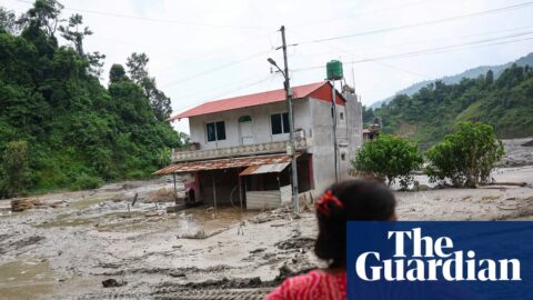 A woman looks on as heavy machinery works in the aftermath of deadly flash floods and a mudslide near the Nepal-Tibet border