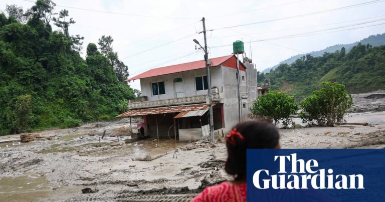 A woman looks on as heavy machinery works in the aftermath of deadly flash floods and a mudslide near the Nepal-Tibet border