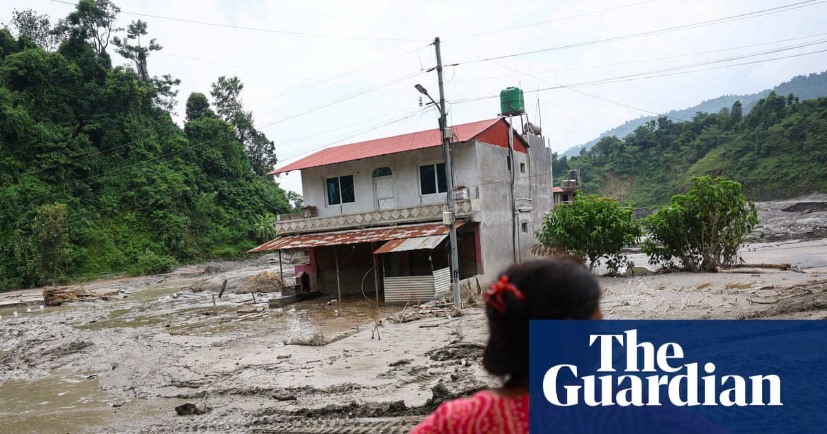 A woman looks on as heavy machinery works in the aftermath of deadly flash floods and a mudslide near the Nepal-Tibet border