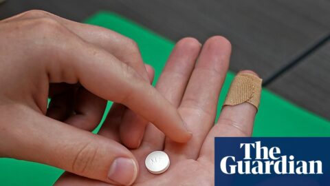A close-up of hands holding a mifepristone pill above an open palm