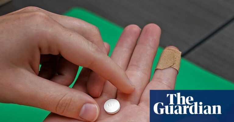 A close-up of hands holding a mifepristone pill above an open palm