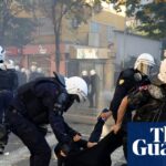 Riot police drag a hooded protester across a crosswalk during clashes in Tirana