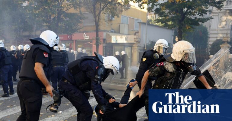 Riot police drag a hooded protester across a crosswalk during clashes in Tirana