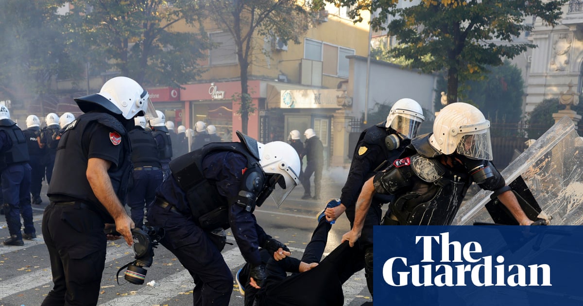 Riot police drag a hooded protester across a crosswalk during clashes in Tirana