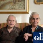 Sisters Mariangela and Giovanna Marras, aged 99 and 101, sit together on a sofa