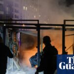 Rescuers stand amid rubble and smoke at a burning building after a drone strike in Kyiv