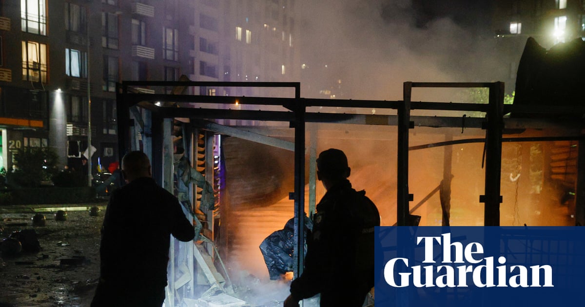 Rescuers stand amid rubble and smoke at a burning building after a drone strike in Kyiv