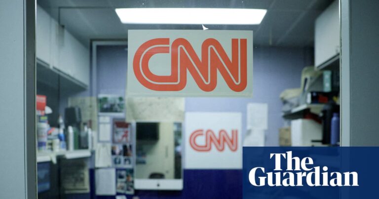 the CNN logo is posted on a small office room