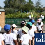 Pupils wearing hats and holding water bottles stand in a line outdoors