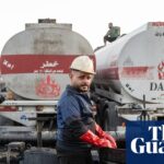 Workers facilitate the offloading of crude oil from trucks on to a tanker ship at the Banyas Oil Terminal in Tartus, Syria