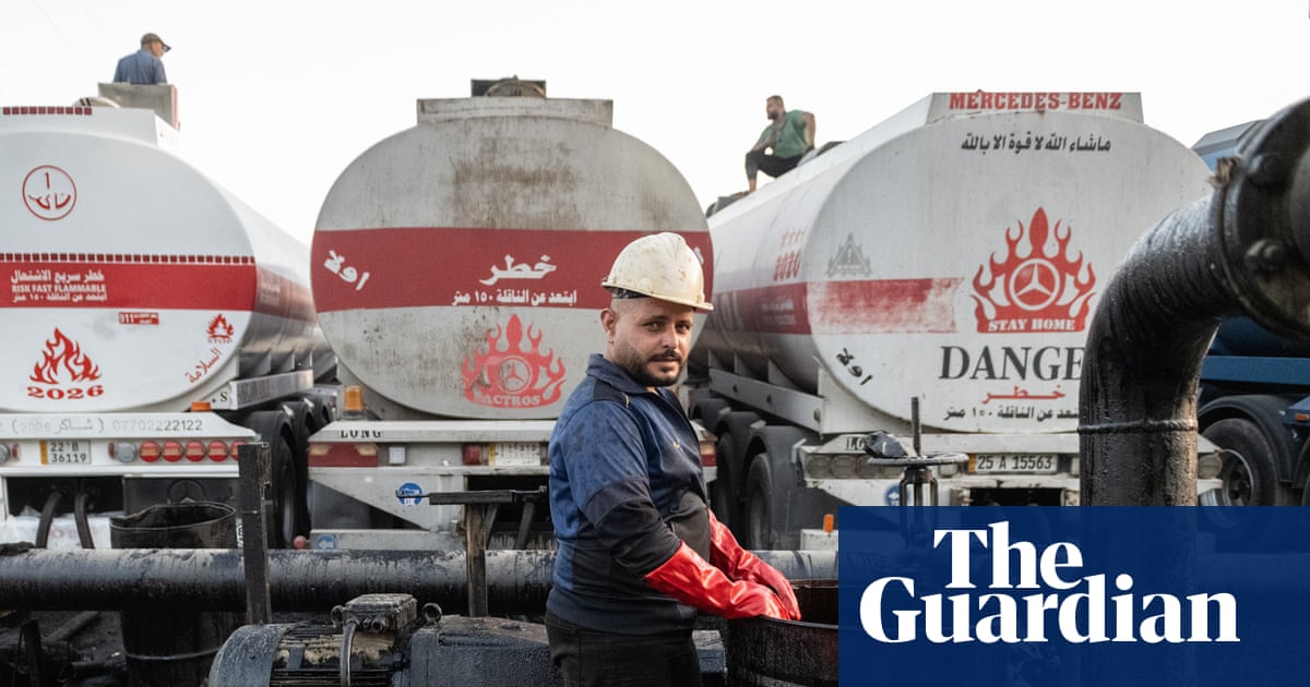 Workers facilitate the offloading of crude oil from trucks on to a tanker ship at the Banyas Oil Terminal in Tartus, Syria